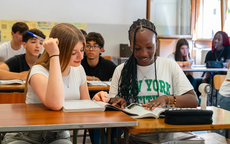 Studenti delle scuole superiori seduti ai banchi di un'aula mentre studiano insieme sui libri di testo