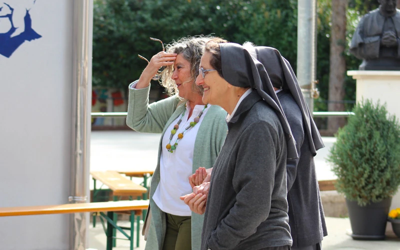 Suore salesiane e una donna laica in un momento di dialogo sereno nel cortile di una struttura